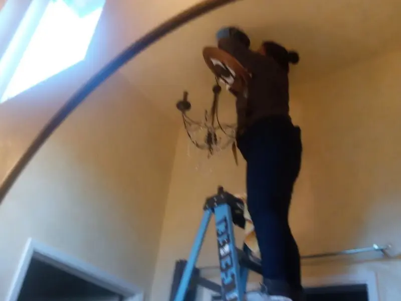 Electrician installing a chandelier in a East Palestine residence